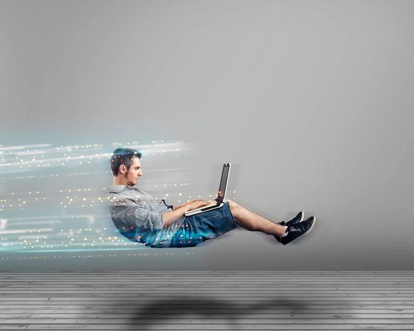 Ein Mann arbeitet mit einem Laptop, während leuchtende digitale Datenspuren Geschwindigkeit und eine schnelle Internetverbindung symbolisieren.